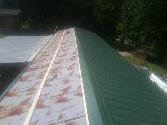 Old rusted panels beside newly installed green metal roofing — Wind Damage Roof Repair by Roofing Brothers in Whitehall