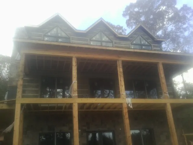Dormers and porch framing on a large log home under construction — Roof Coating work by our crew in Whitehall